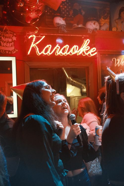 People singing karaoke together into a microphone (illustrative photograph)