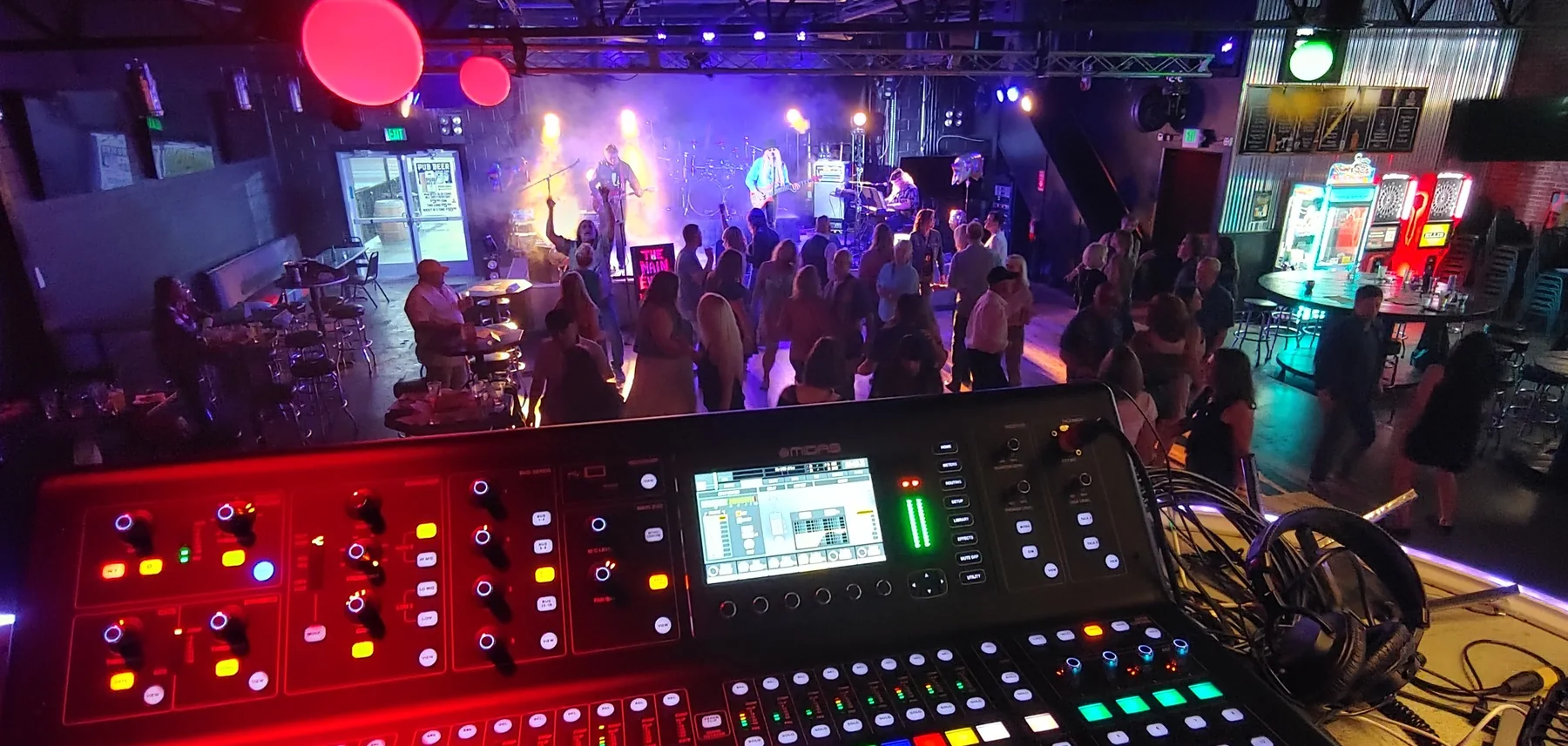 Mixing desk in front of an illuminated live stage and audience